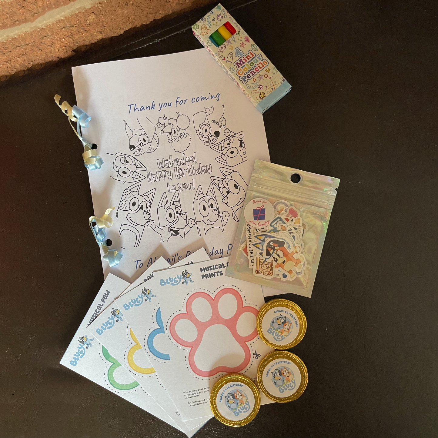 A single activity pack, surrounded by the other contents of the pack including crayons, stickers, and chocolate coins.